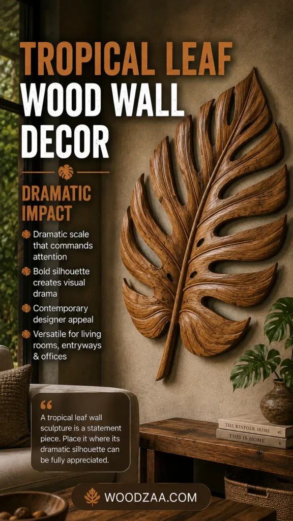 Pinterest graphic titled "TROPICAL LEAF WOOD WALL DECOR: DRAMATIC IMPACT." The image features a large, carved wooden tropical leaf mounted as wall art above a wooden console table. Bullet points on the left describe its "Dramatic scale" and "Bold silhouette," accompanied by a quote about statement wall pieces. The room features cozy decor, including stacked design books ("THE KINFOLK HOME", "THIS IS HOME"), a potted palm plant, and a sofa. The website logo WOODZAA.COM is centered at the bottom.